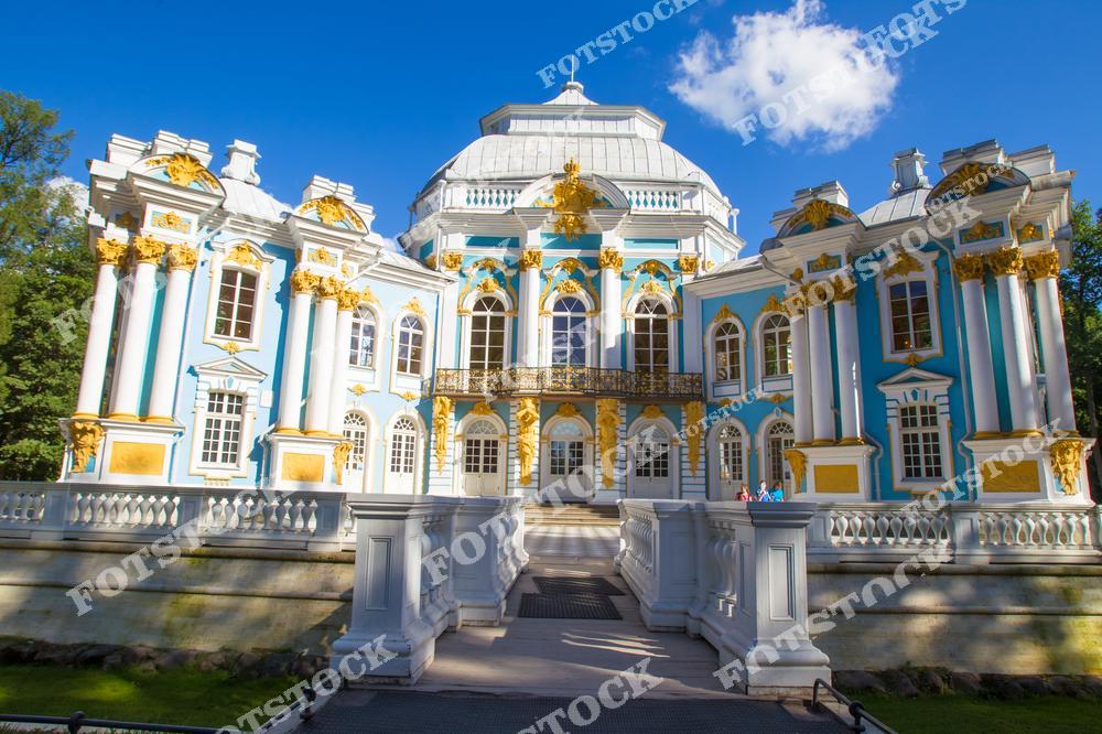 На фотографии изображен павильон "Эрмитаж", расположенный в Екатерининском парке в Царском Селе (Пушкине). Этот неоклассический павильон украшен колоннами и скульптурами. Вокруг него раскинулся живописный парк с цветущими клумбами и зелеными насаждениями. Летнее солнце подчеркивает архитектурную гармонию и природную красоту этого исторического места.